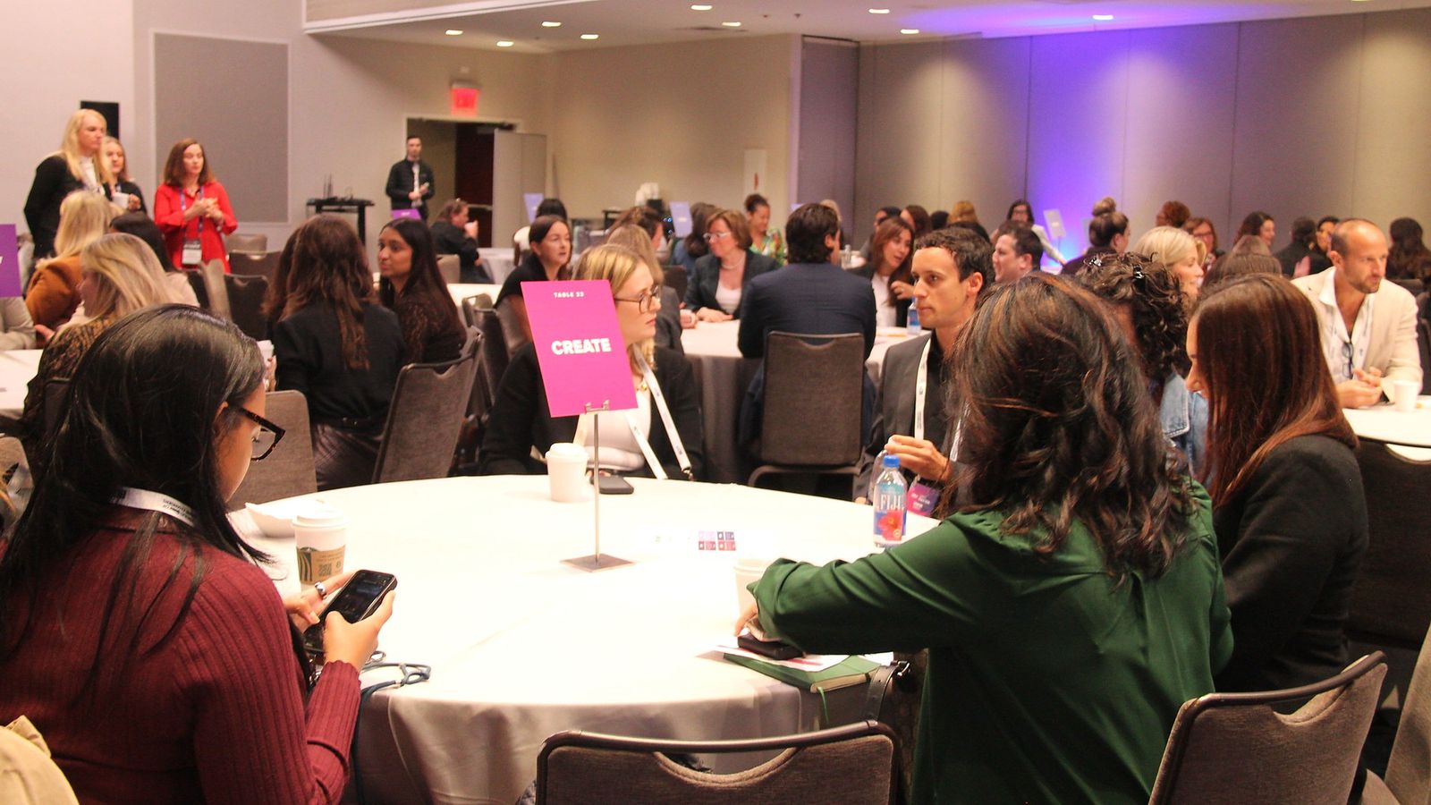 Attendees at a round table with a pink Create sign in the center
