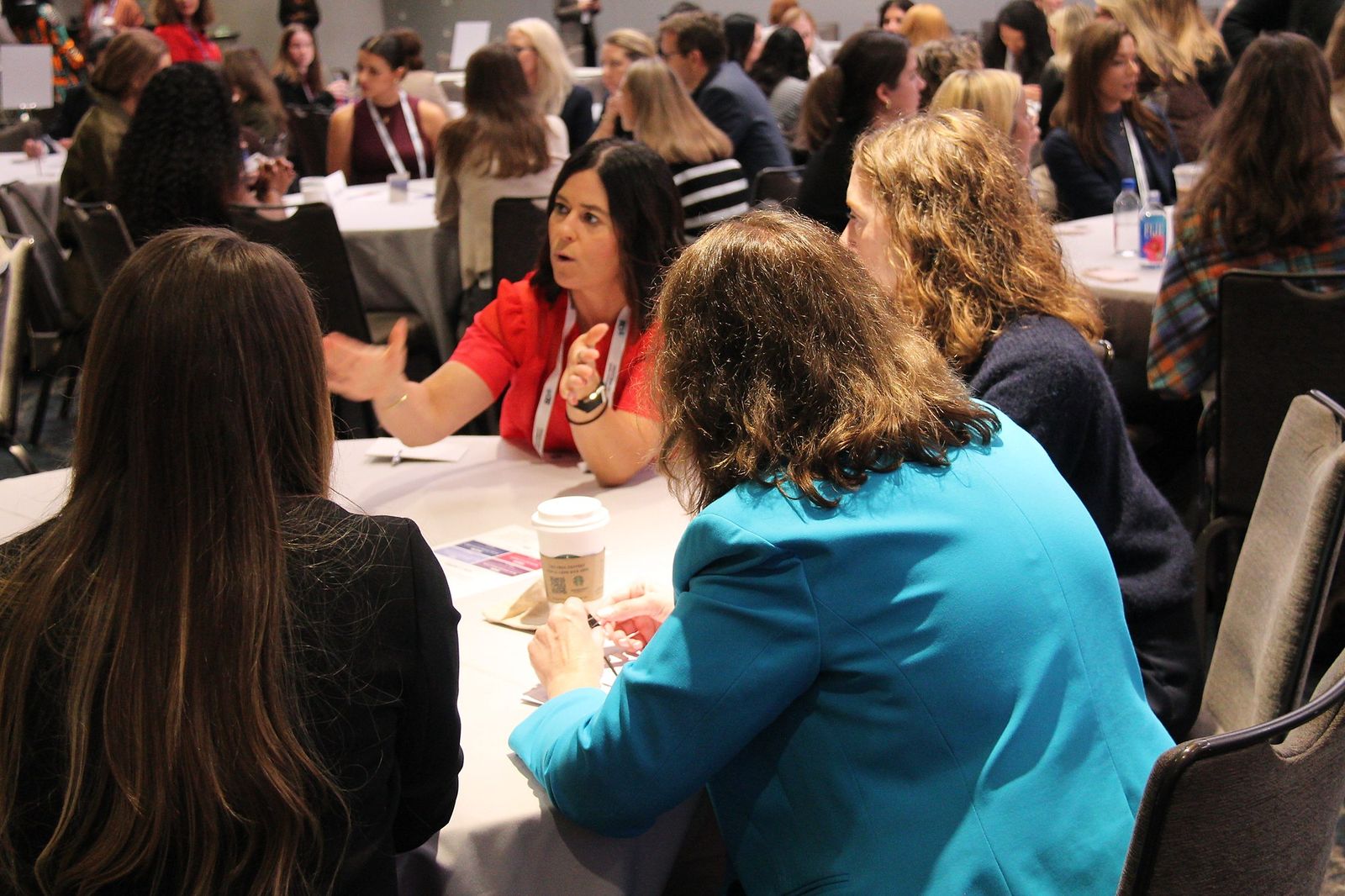 An attendee gestures while others at her table listen
