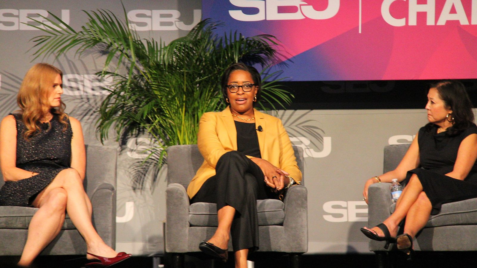 Three panelists seated on stage during the college athletics session