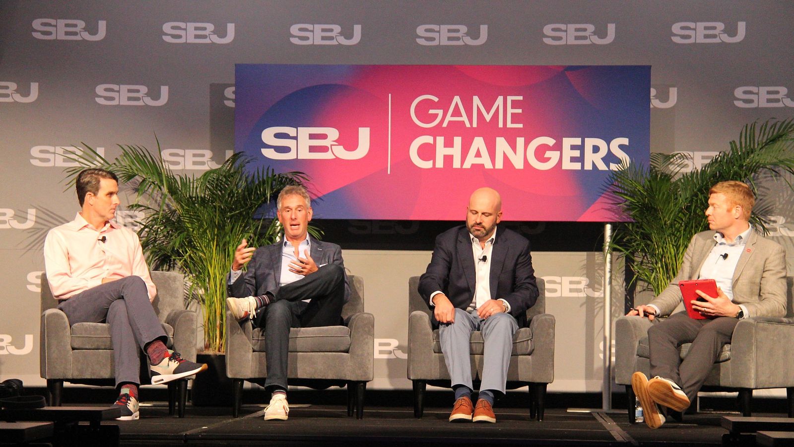 Four men seated on stage during the prediction markets panel as the second from left speaks