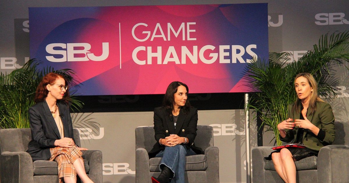 Three women seated on stage during the AI panel as the moderator speaks