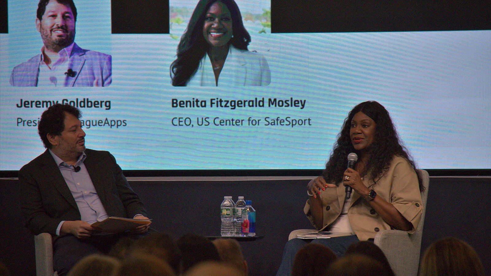 Benita Fitzgerald Mosley speaking on stage beside Jeremy Goldberg