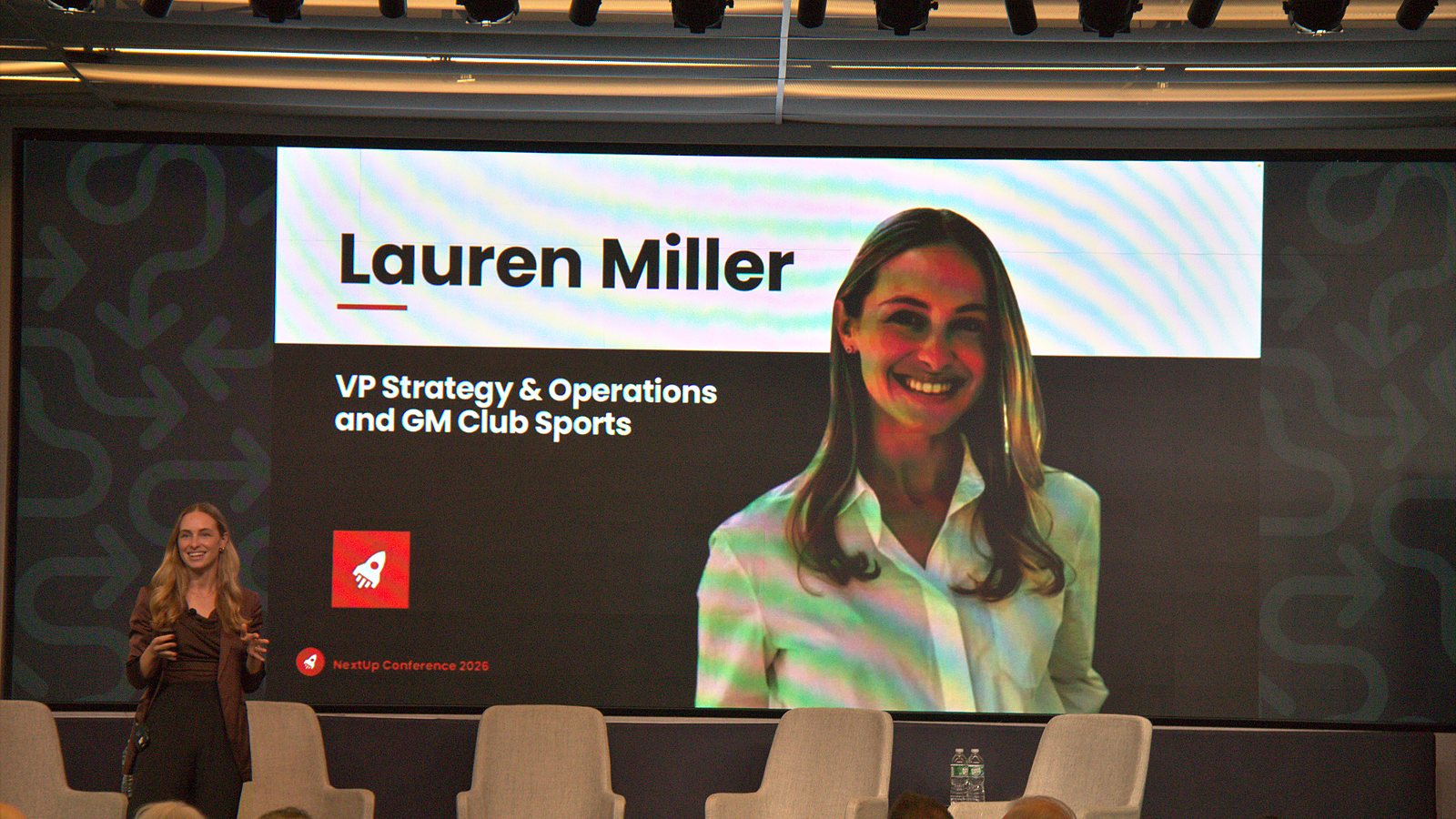 Lauren Miller speaking on stage in front of a slide with her name and title
