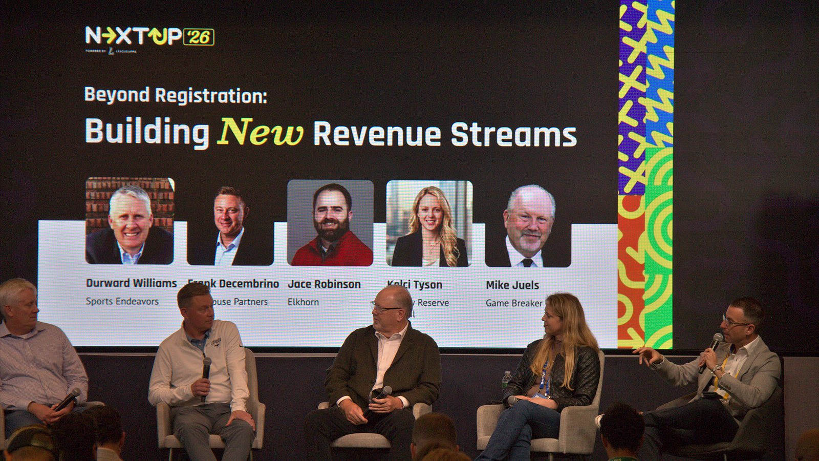Panelists seated on stage beneath a slide titled Beyond Registration: Building New Revenue Streams